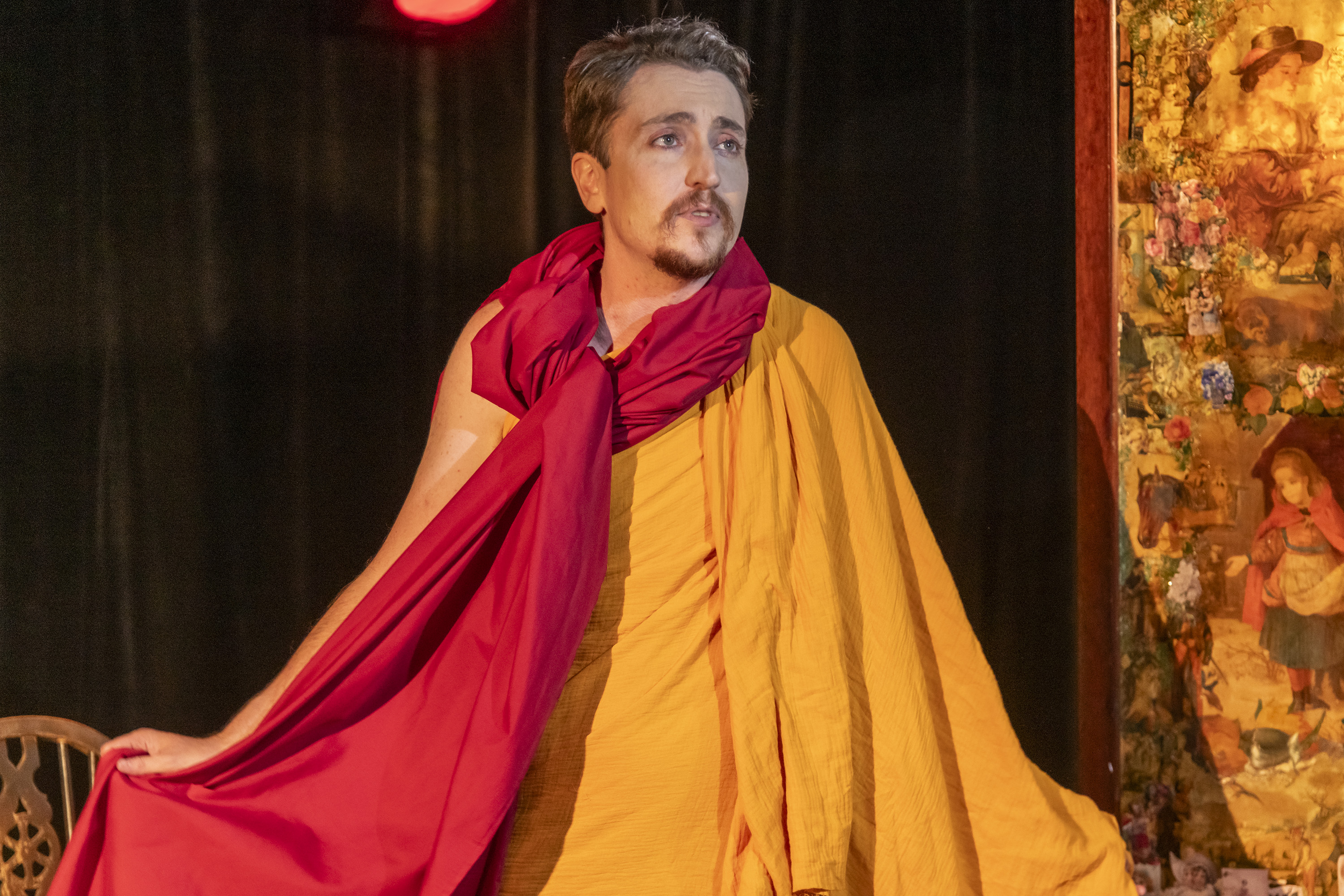 Head to thigh photo showing Cloud Quinn onstage wearing yellow and red Buddhist monk's robes.